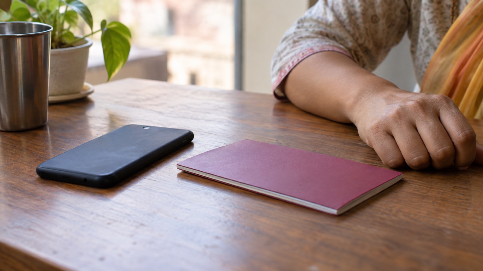 Representative image of a smartphone and closed bank passbook on a desk