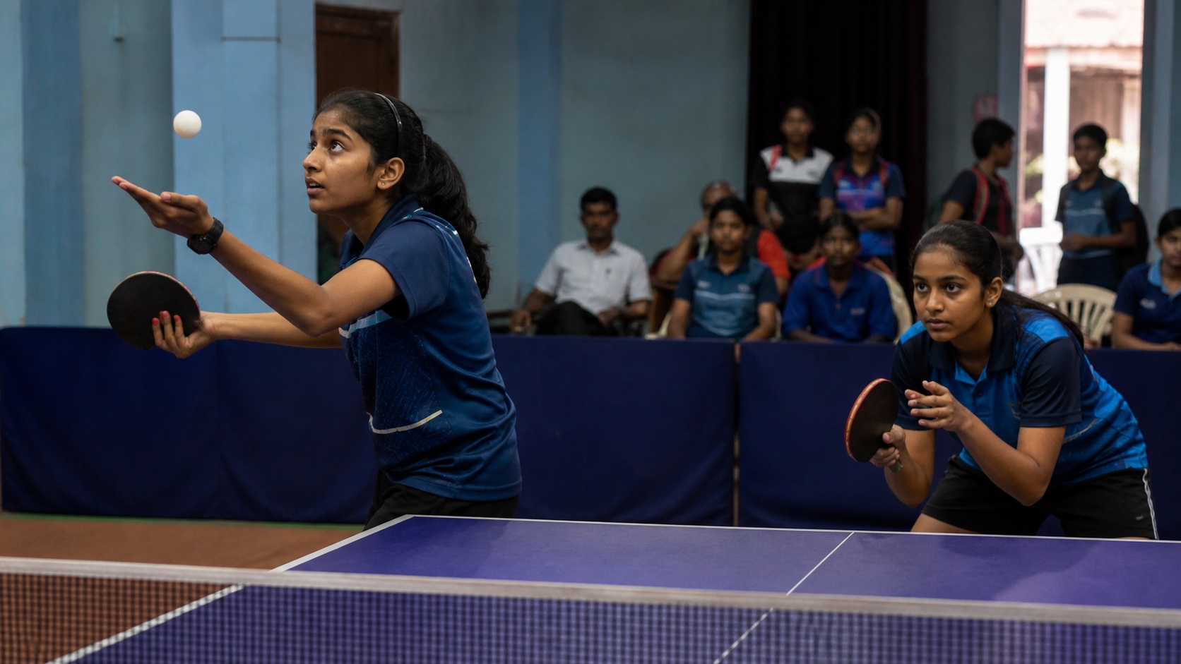 Schoolgirls playing a competitive table-tennis match inside a Varanasi sports hall